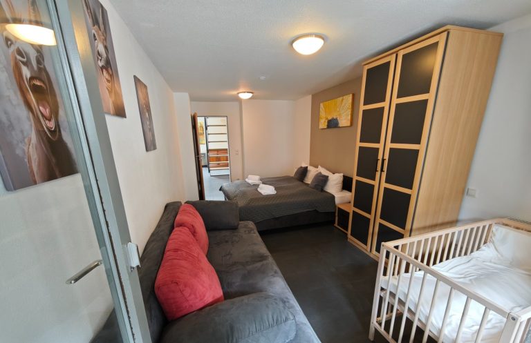 Ferienwohnung Altstadtquartier 16 – Schlafzimmer mit Doppelbett, Schlafcouch & Balkonblick, moderne Akzentwand, ideal für Familien & Gruppen