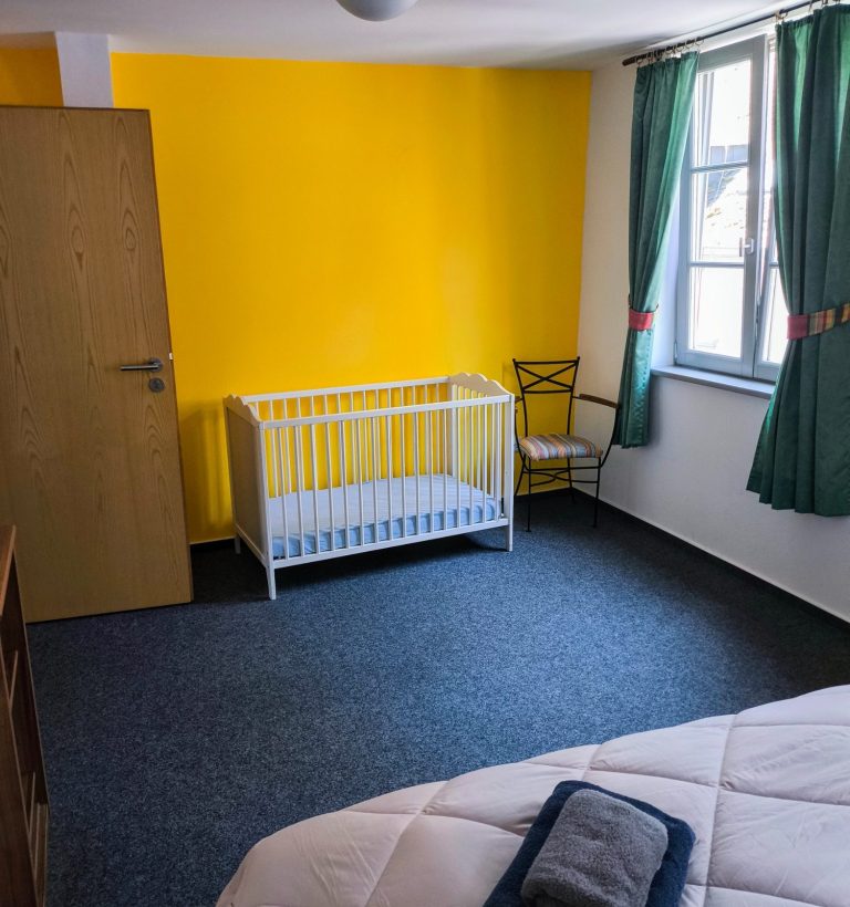 Schlafzimmer mit Doppelbett, Altstadtblick und Blick zur Burg Stahleck – Ferienwohnung Altstadtquartier 16