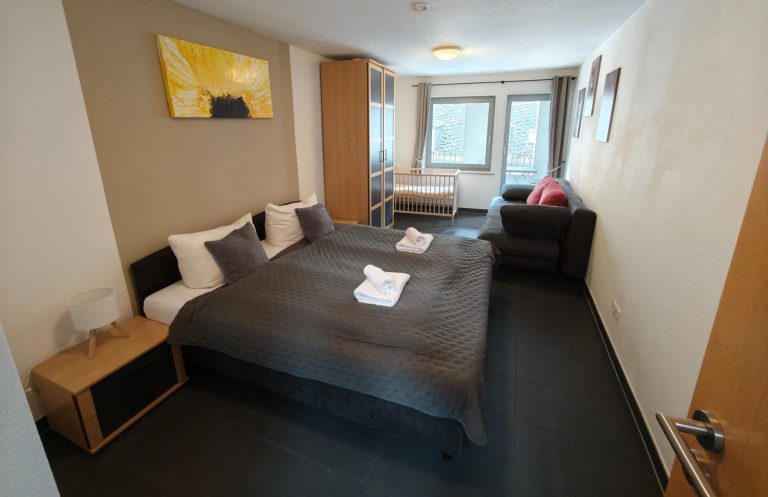 Ferienwohnung Altstadtquartier 16 – Schlafzimmer mit Doppelbett, Schlafcouch & Balkonblick auf Altstadt Bacharach, für Familien & Gruppen