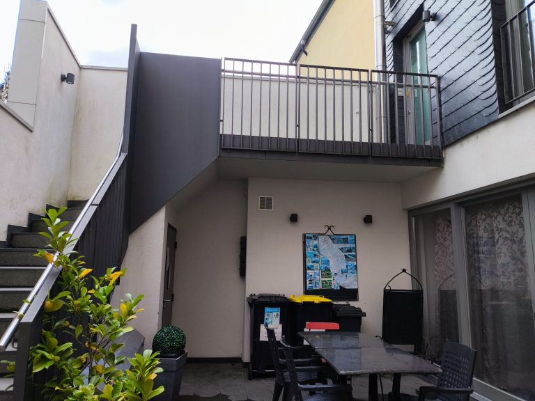 Innenhof mit Außentreppe und korrekt markierten Schlüsselboxen neben der Kellertür – Ferienwohnung Altstadtquartier 16 in Bacharach