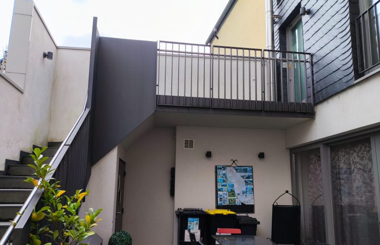Innenhof mit Außentreppe und korrekt markierten Schlüsselboxen neben der Kellertür – Ferienwohnung Altstadtquartier 16 in Bacharach