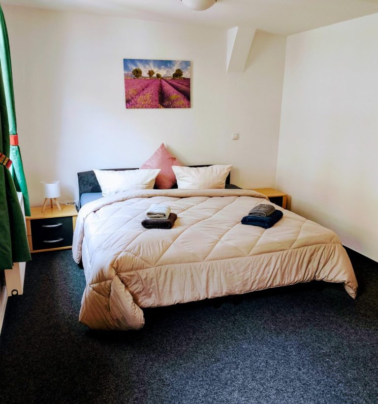 Schlafzimmer mit Doppelbett, Altstadtblick und Blick zur Burg Stahleck – Ferienwohnung Altstadtquartier 16